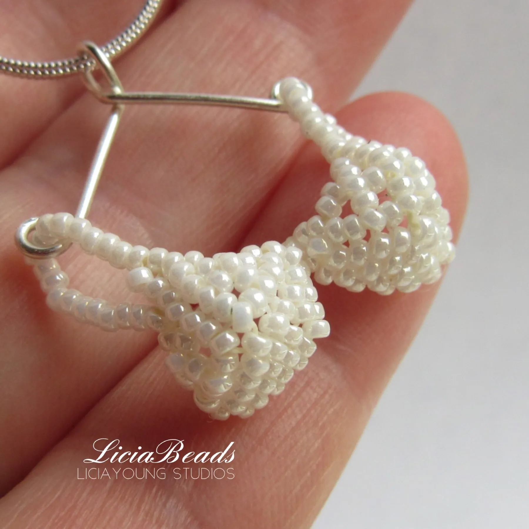 Itsy bitsy beaded bra pendant supported by a sterling hanger.